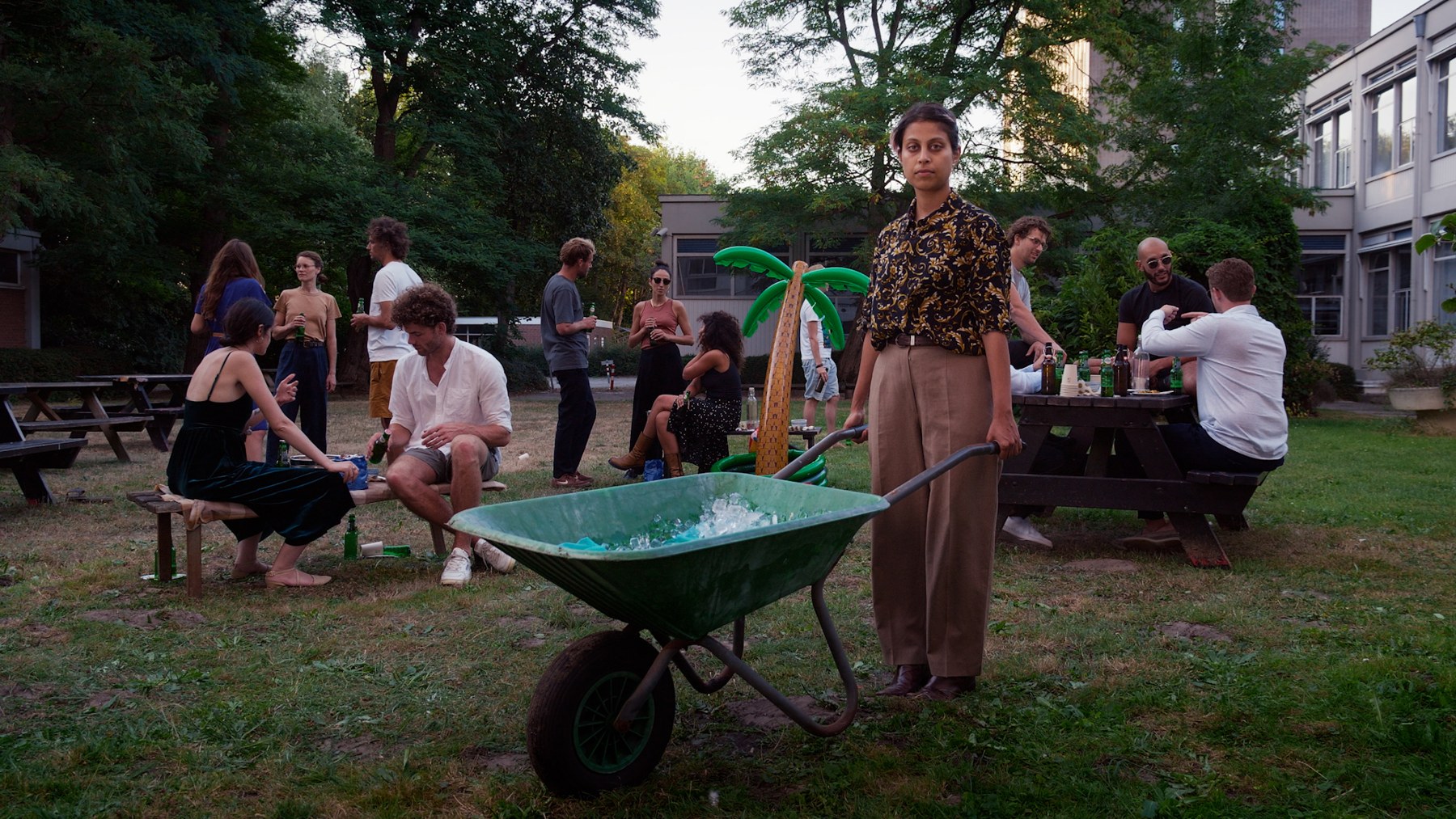 People gathered around a wheelbarrow at a garden party.